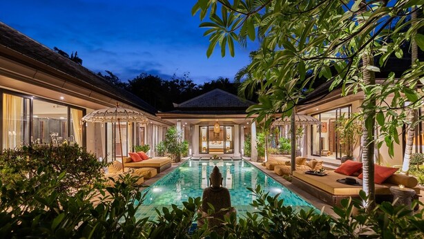 Un espace luxueux aménagé au bord de la piscine, offrant une vue dégagée sur celle-ci, des sièges confortables et une végétation luxuriante.