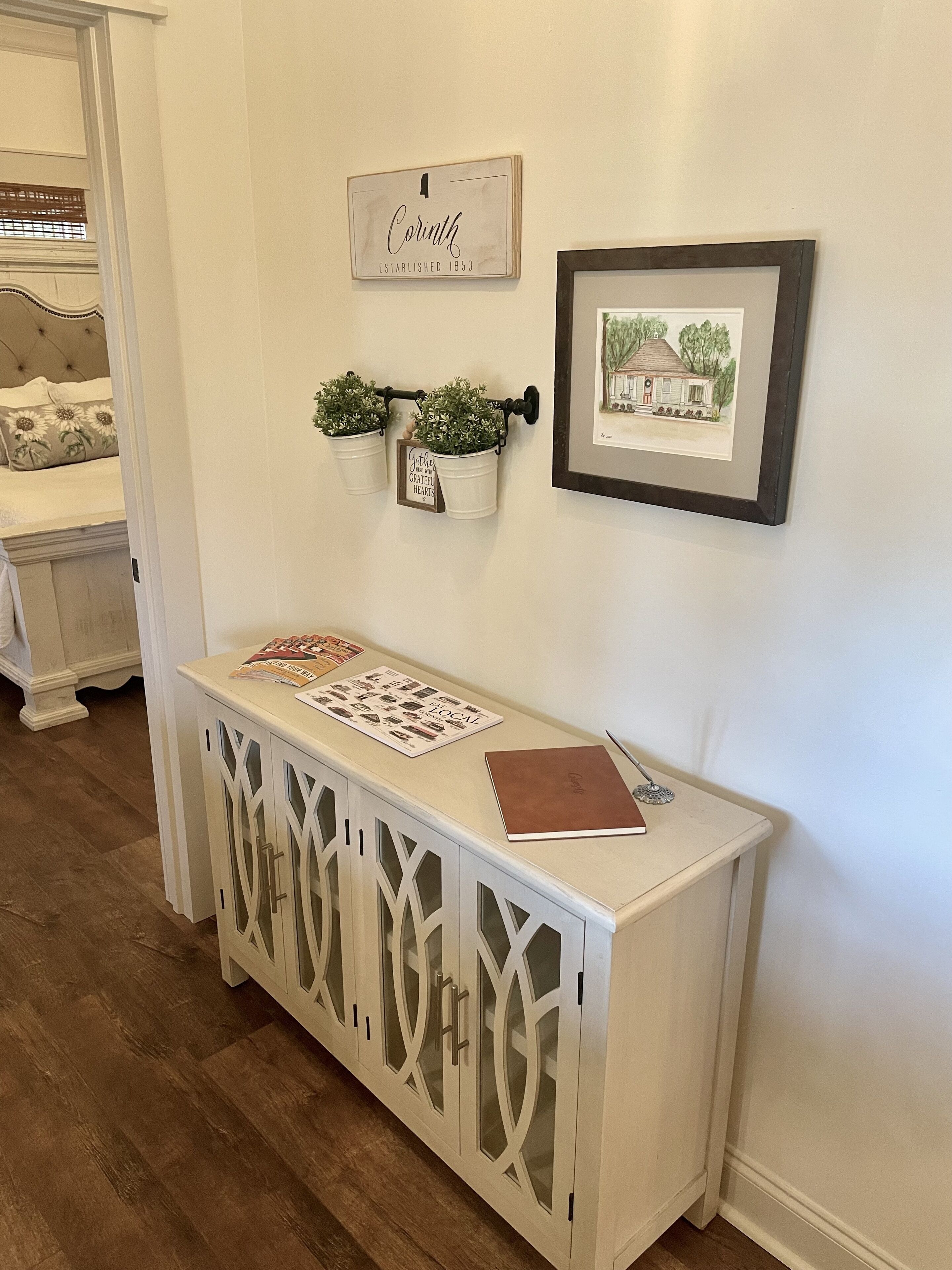 A white console table with a framed picture and a sign above it.