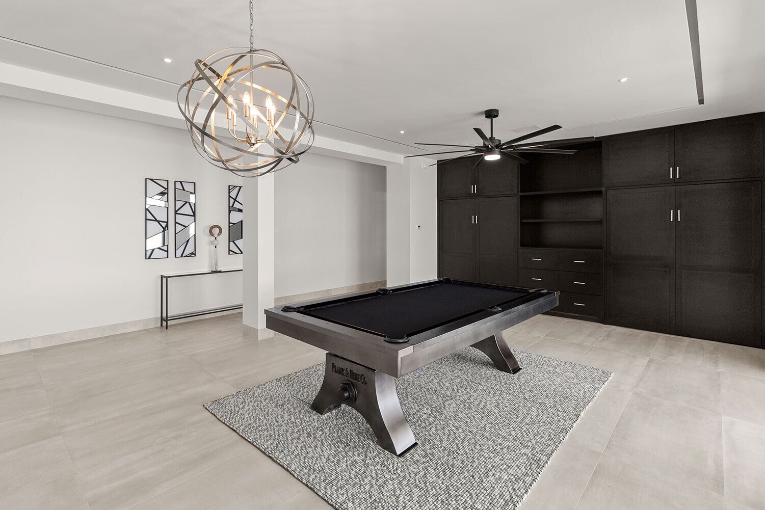 Una habitación moderna con mesa de billar, ventilador de techo y una lámpara decorativa.