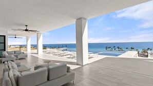 Un área exterior moderna con piscina, sillones de descanso y vista al océano.