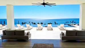 Un área de descanso moderna con vistas al océano, que presenta sillones y sofás blancos dispuestos en una distribución amplia.