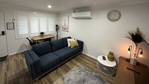 A modern living room with a dark blue sofa, a round coffee table, and a small side table with decorative items.