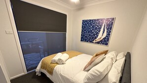 A hotel room with a bed, a painting, and a view through a sliding door.