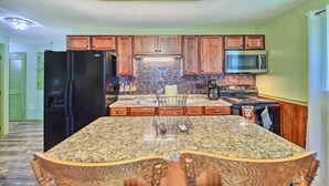 A kitchen with wooden cabinets, a granite countertop, a stainless steel refrigerator, a microwave, and a stove.