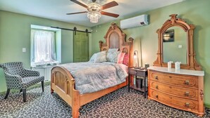 Un dormitorio con cama, cómoda, silla, ventilador de techo y aire acondicionado.