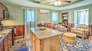 Una cocina amplia con una isla central, armarios de madera y un ventilador de techo.