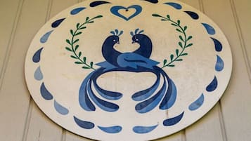 Objeto circular con diseño de pavo real, rodeado de formas de lágrima azules y un corazón en la parte superior.