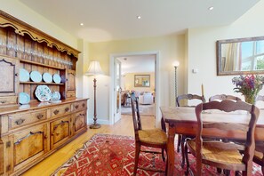 Un coin repas comprenant un buffet en bois, un tapis à motifs rouges et une table à manger avec des chaises.