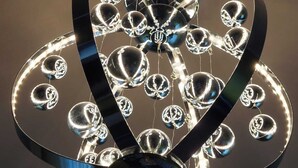 Ett tak med en dekorativ, reflekterande, metallisk struktur som har sfäriska element och böjda linjer.