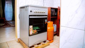 Una cocina con horno blanco, un mueble de madera y piso de baldosas.