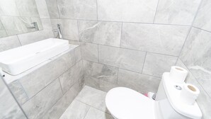 Un baño con lavamanos blanco, inodoro y zona de ducha.
