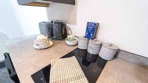 Una encimera de cocina con una tetera, una cafetera, un tazón de cereal y una caja de té Purika.