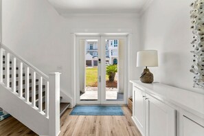 Ein Flur mit einer weißen Treppe, einem blauen Teppich und einer Tür, die nach draußen führt.