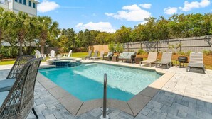 Une piscine rectangulaire avec une terrasse carrelée, entourée de chaises longues et d’une clôture en bois.