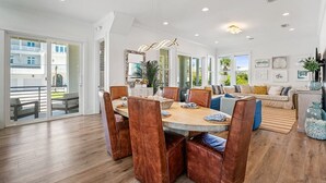 Un vaste espace dédié à la salle à manger, avec une grande table ronde, des fauteuils en cuir et une vue sur l’extérieur grâce à de grandes fenêtres.
