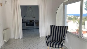 Une pièce avec un fauteuil à rayures, une cheminée et une vue sur la mer.