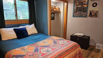Ein Schlafzimmer mit einem großen Bett, einem Fenster, einer Tür und einer Wand mit Postern und Schallplatten.