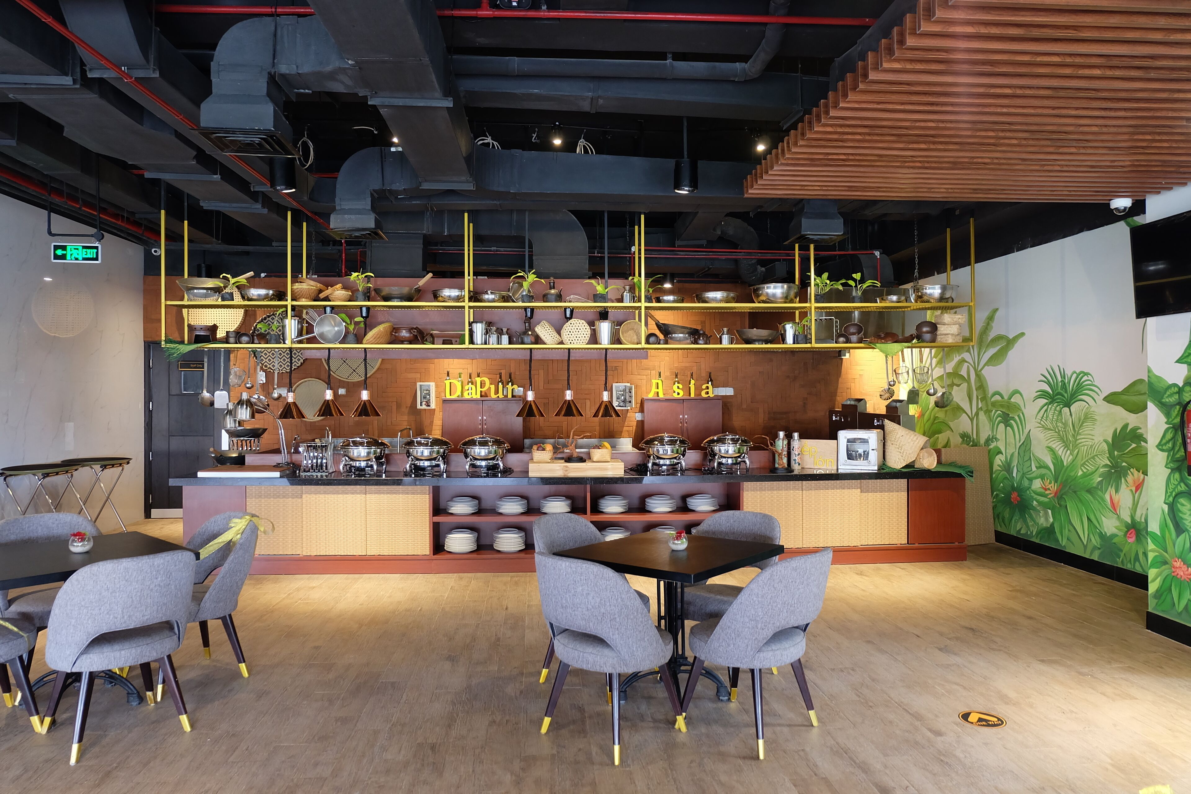 Un restaurante con mostrador de madera, varias estaciones de cocina y una zona de estar con mesas y sillas.