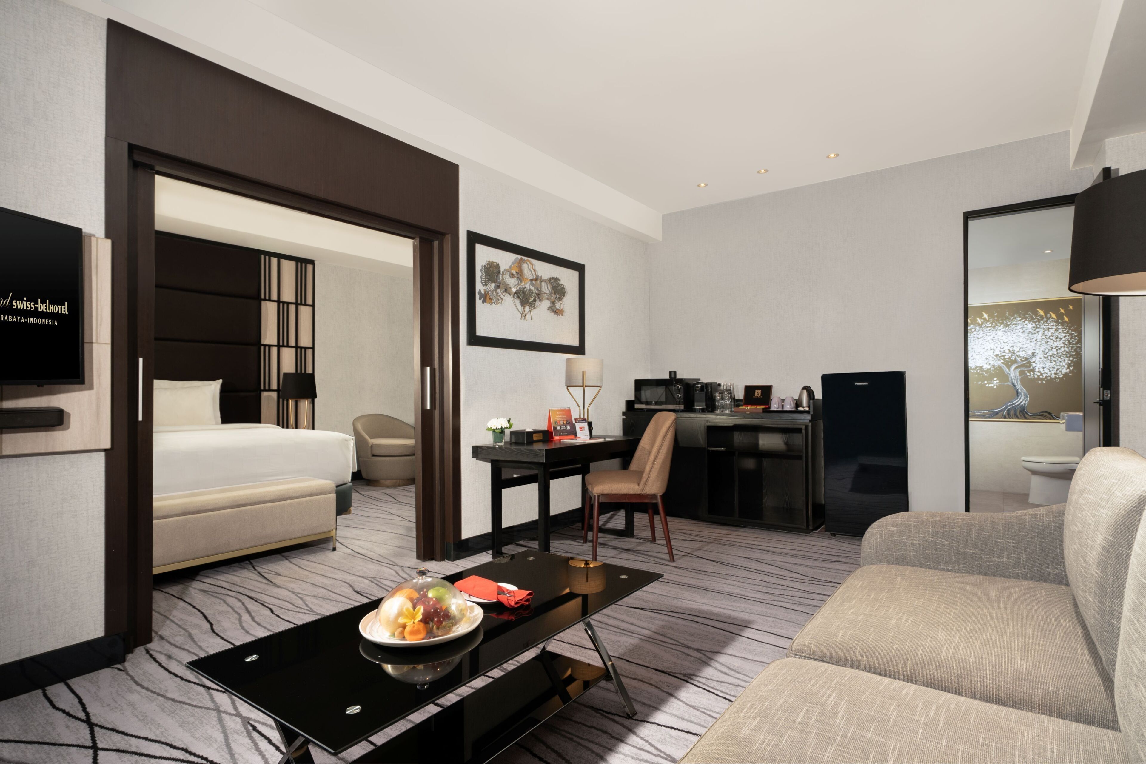 A hotel room with a bed, a desk, a chair, a sofa, and a television.