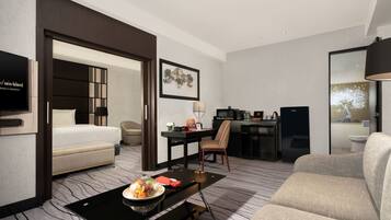 A hotel room with a bed, a desk, a chair, a sofa, and a television.