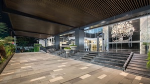 Een modern gebouw met een overdekte doorgang, grote ramen en een decoratieve boomsculptuur.