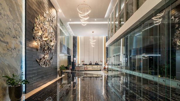 Een moderne lobby met een marmeren vloer, een receptiebalie en een groot kunstwerk aan de muur.