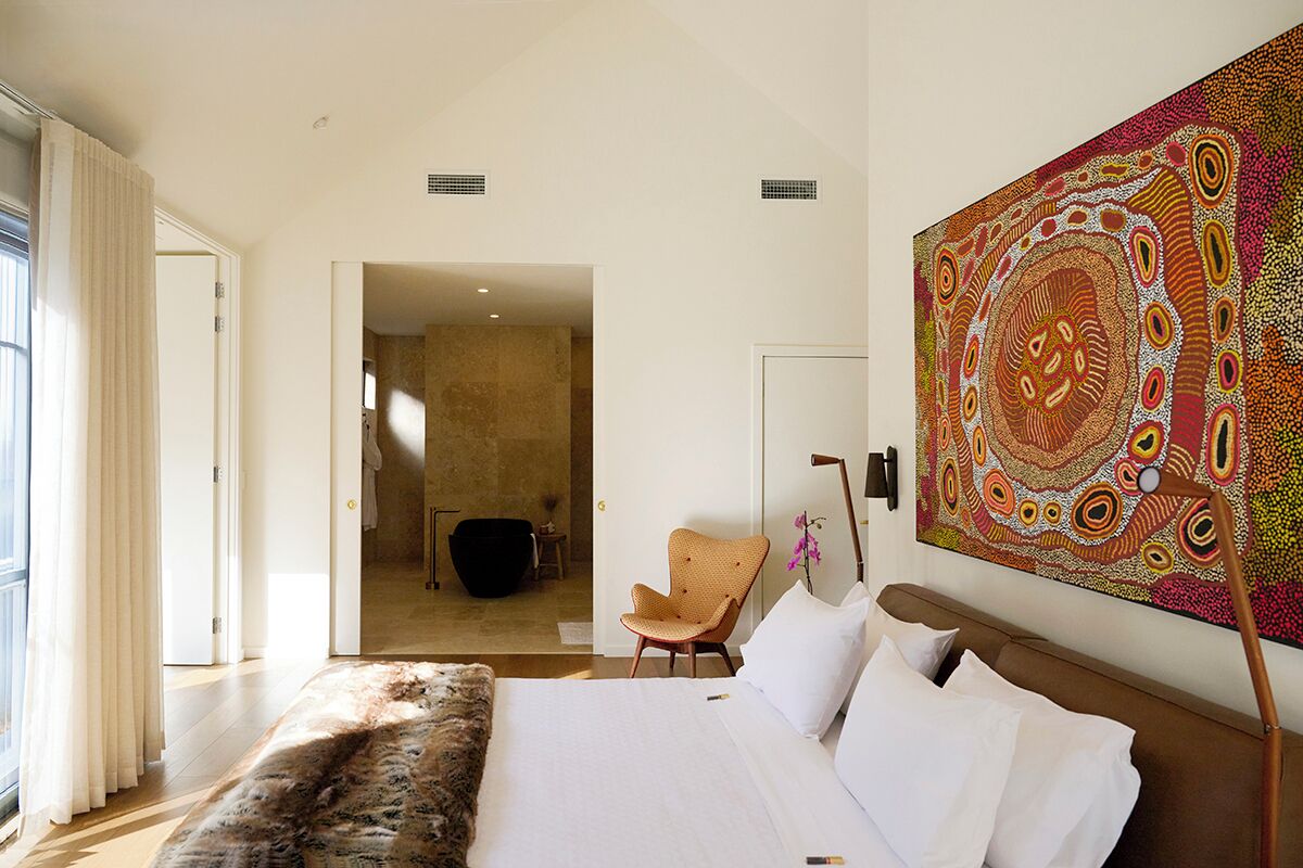 Un dormitorio con una cama grande, una silla y un tapiz colorido.