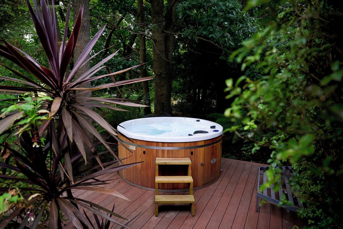 A hot tub on a wooden deck surrounded by dense foliage.