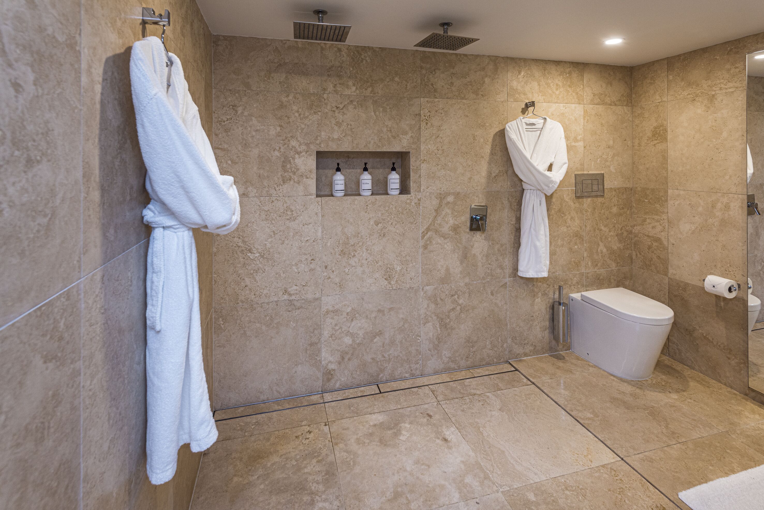 A modern bathroom with a walk-in shower, a toilet, and a towel rack.