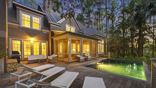 Ein zweistöckiges Haus mit Swimmingpool, Sitzgelegenheiten im Freien und einer überdachten Terrasse.