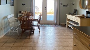 Un comedor con una mesa y sillas, un armario de madera y una puerta que da al exterior.