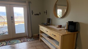Una habitación con un aparador de madera, un espejo y vistas a través de un ventanal.