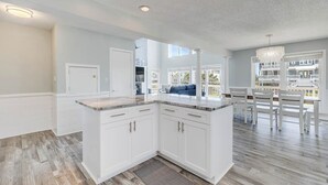 A spacious kitchen with white cabinetry, a marble countertop, and a view to the outdoor balcony area.