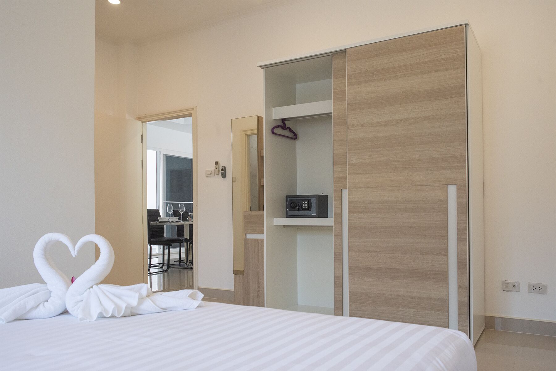 A hotel room with a bed, a desk with a chair, and a wardrobe.