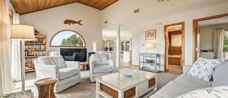 A spacious living area with a television, sofas, a coffee table, and a bookshelf.