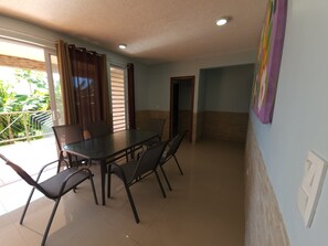 Un comedor con una mesa, sillas, una puerta corrediza de vidrio y vistas a zonas verdes.