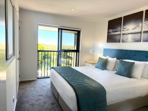 A bedroom with a large bed, a balcony, and a view of the outdoors.