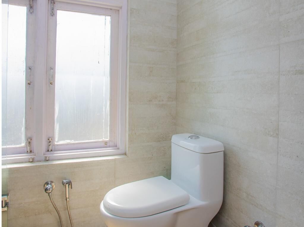 Une salle de bain avec des toilettes, une fenêtre et une douche.