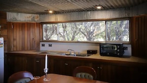 Eine Küche mit Holzausstattung, einem Spülbecken, einem Toaster und einem großen Fenster mit Blick auf Bäume.