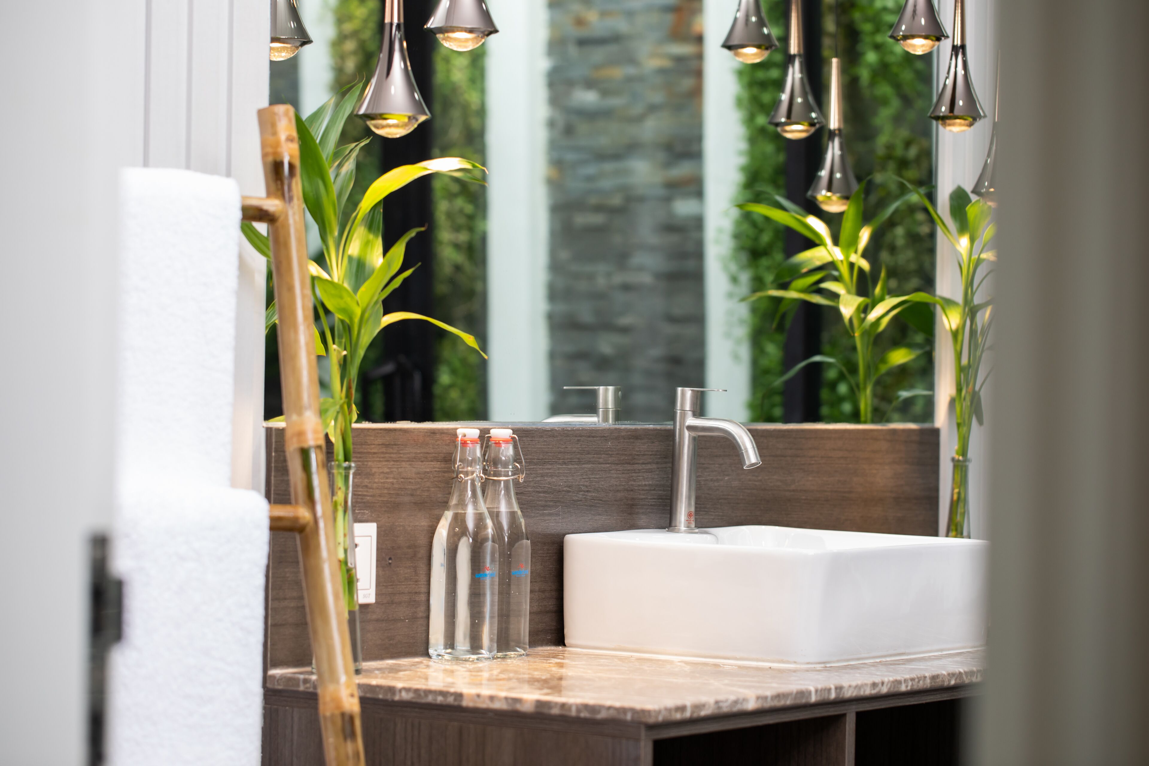Un baño con tocador de madera, un lavabo blanco y luces colgantes.