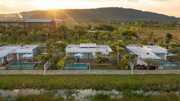 Un complejo turístico con varias edificaciones, piscinas al aire libre y abundante vegetación.