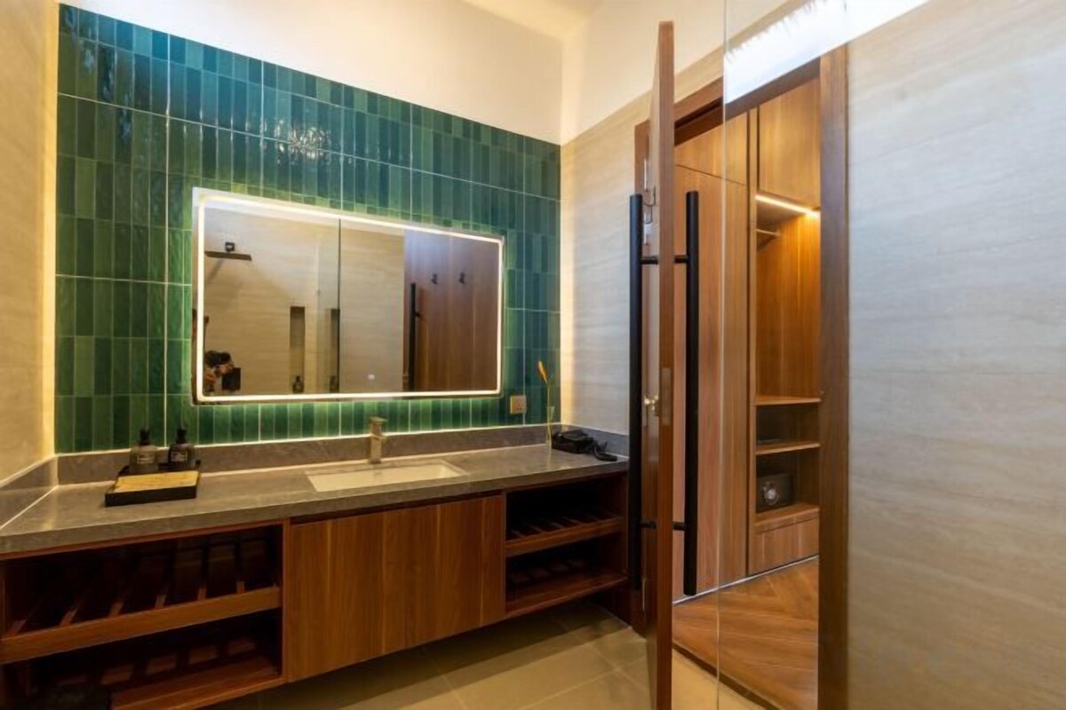 A bathroom with a mirror, sink, and wooden cabinets.