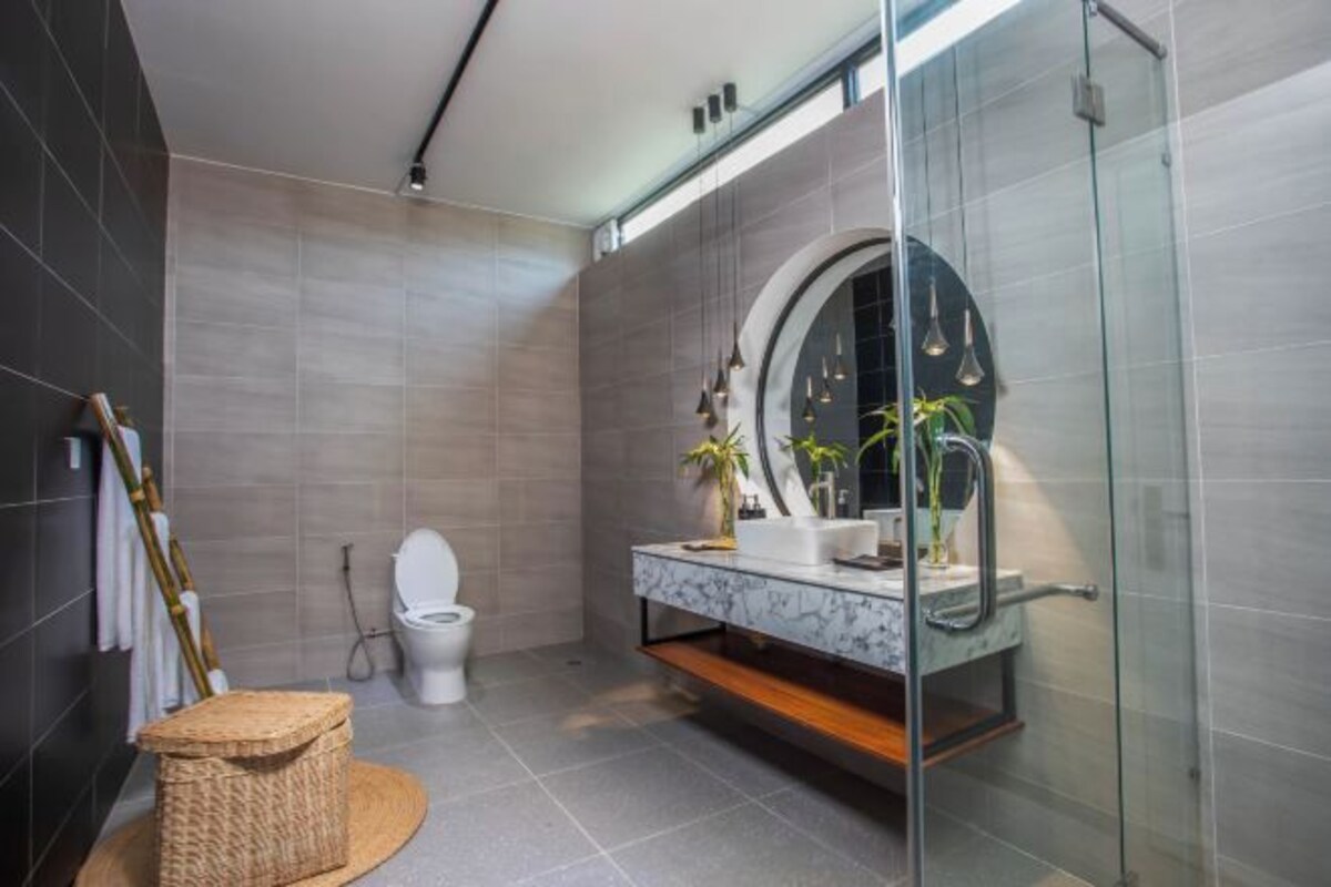 Um banheiro moderno com box de vidro, toucador de mármore e vaso sanitário.