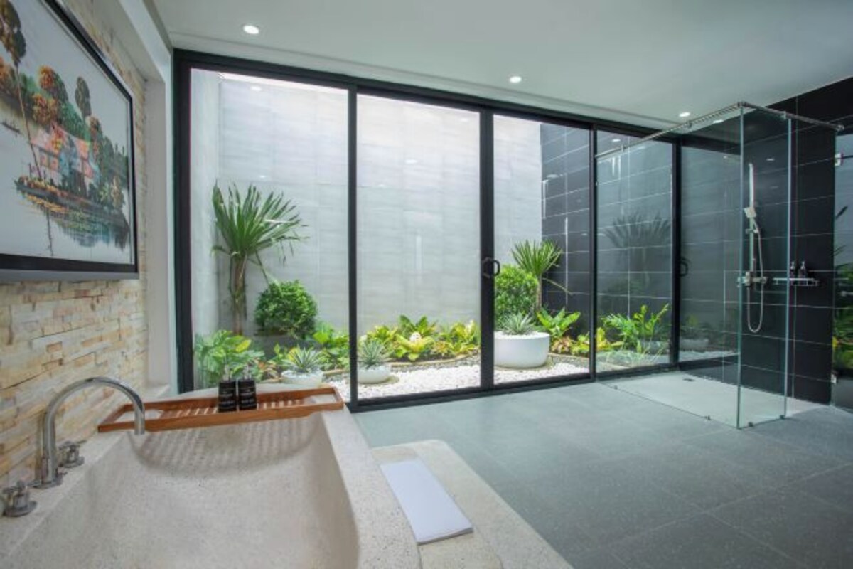 A modern bathroom with a large window, a bathtub, and a shower area.
