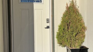 A white door with a window, a small potted plant, and a wall-mounted lantern. - Cozy little place 
15 min from the strip  (Las Vegas)