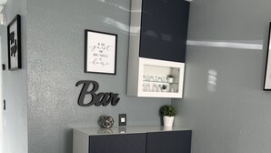 A modern reception area with a grey textured wall, a dark grey console with a potted plant, a framed quote, and a marble-tiled floor. - Cozy little place 
15 min from the strip  (Las Vegas)