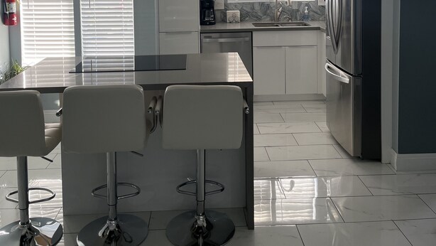 A modern kitchen with a bar area, stainless steel appliances, and a 'home' sign on the wall. - Cozy little place 
15 min from the strip  (Las Vegas)