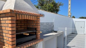 Forno de tijolos ao ar livre com chaminé, painel de azulejos e grelha de metal.