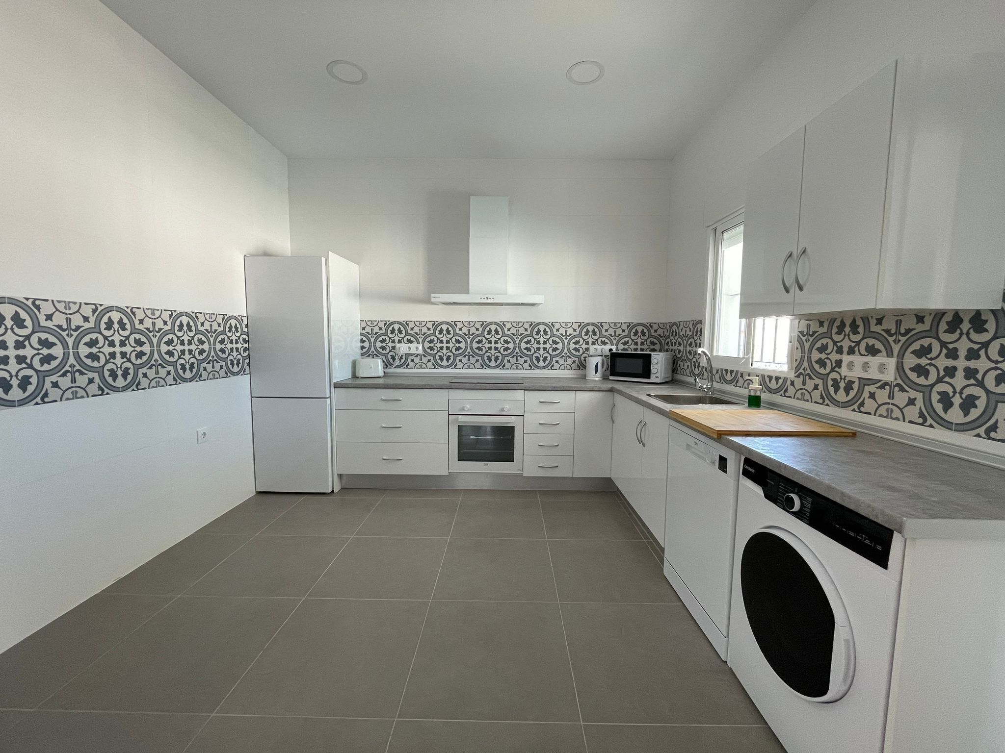 A kitchen with a washing machine, a microwave, and a toaster.