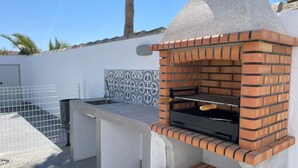 An outdoor brick oven grill with a tiled backsplash and a metal countertop. - Miamar II House in Chiclana (Chiclana)